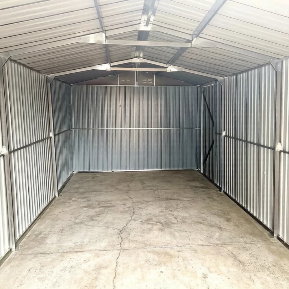 Empty metal storage shed with corrugated walls and concrete floor.