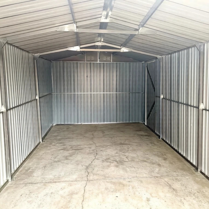 Empty metal storage shed with corrugated walls and concrete floor.